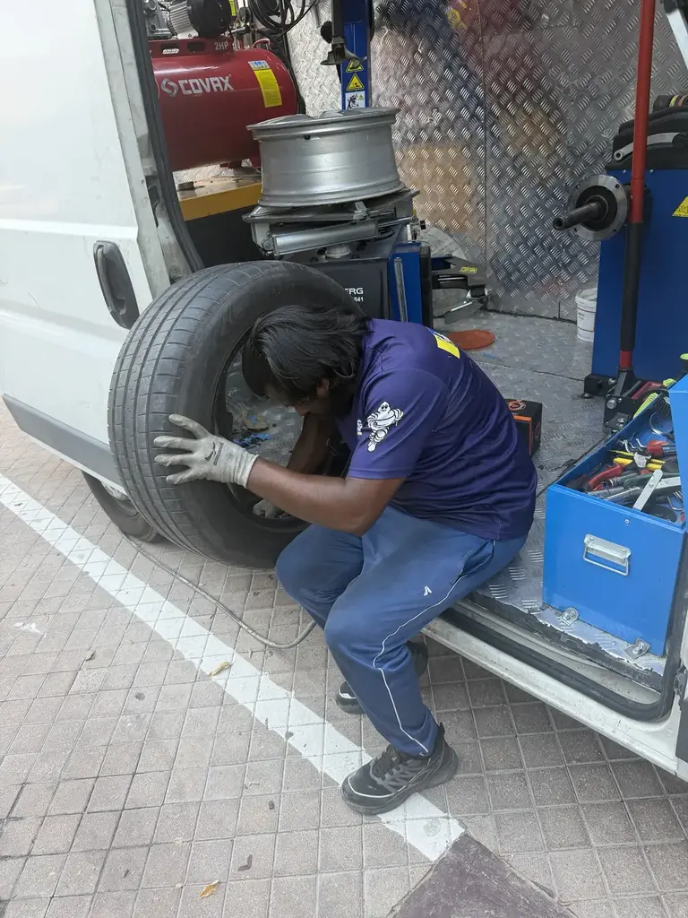 Technician fitting a tyre with mobile service equipment